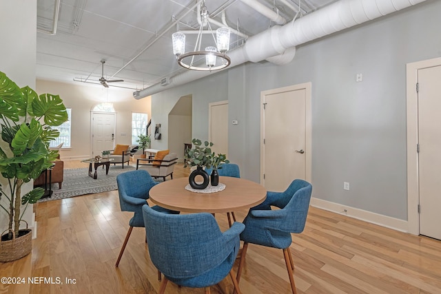 dining space featuring ceiling fan with notable chandelier and light hardwood / wood-style flooring