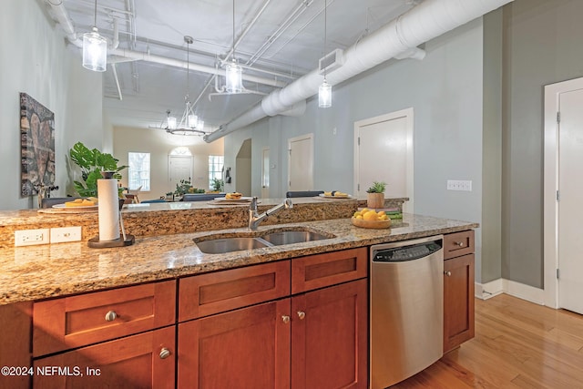 kitchen featuring dishwasher, sink, light stone counters, light hardwood / wood-style floors, and decorative light fixtures