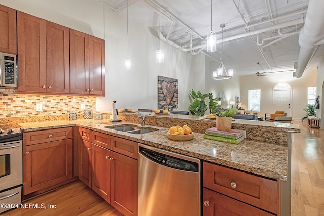 kitchen featuring pendant lighting, sink, light stone countertops, tasteful backsplash, and stainless steel appliances