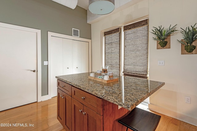 kitchen featuring a kitchen breakfast bar, a center island, dark stone countertops, and light hardwood / wood-style floors