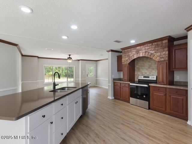 kitchen with light wood-type flooring, a textured ceiling, stainless steel appliances, sink, and white cabinets