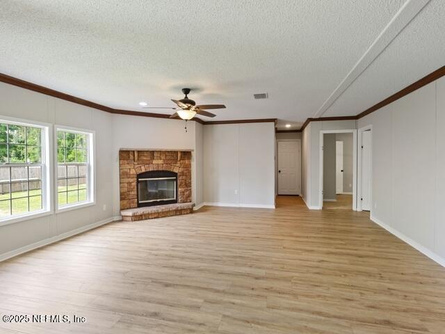 unfurnished living room with crown molding, a textured ceiling, and a brick fireplace