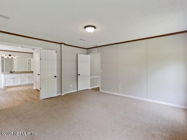 unfurnished bedroom featuring light colored carpet, ornamental molding, a textured ceiling, and a closet