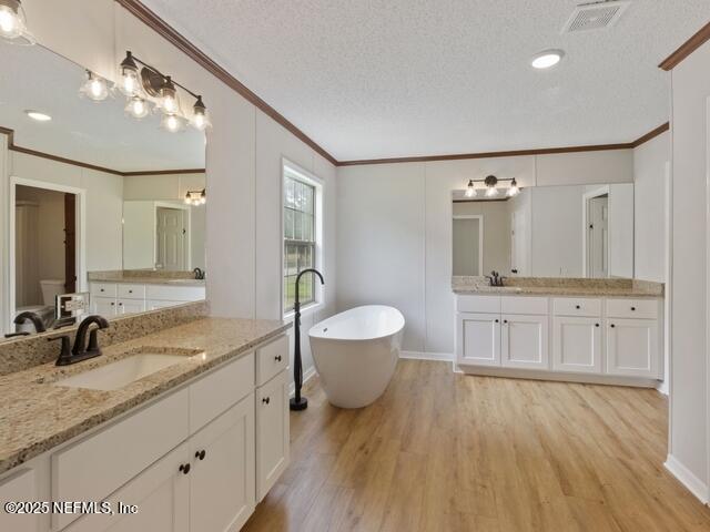 bathroom featuring vanity, a bathing tub, crown molding, hardwood / wood-style flooring, and a textured ceiling