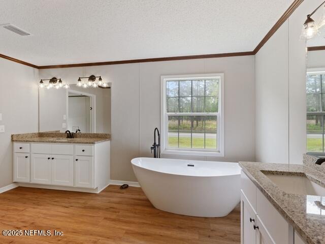 bathroom with vanity, a textured ceiling, hardwood / wood-style flooring, and a bathing tub