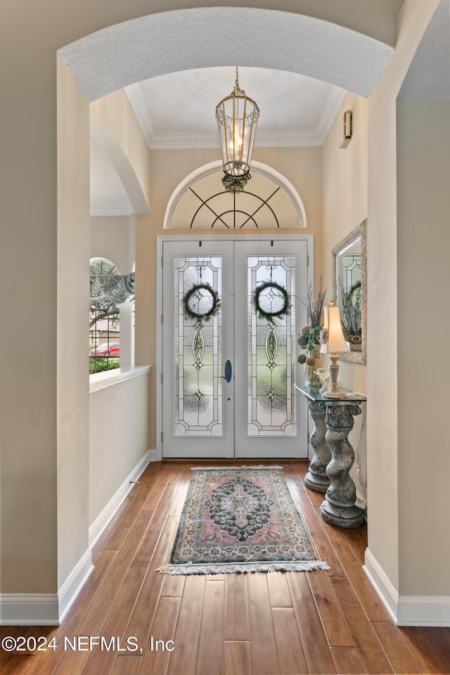 foyer entrance featuring french doors, a chandelier, and ornamental molding