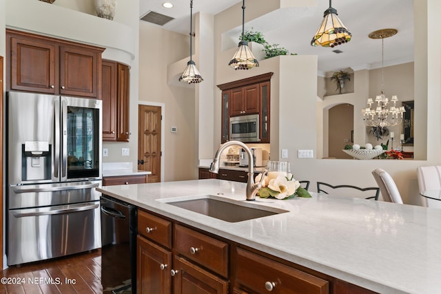 kitchen with sink, light stone counters, a notable chandelier, pendant lighting, and appliances with stainless steel finishes