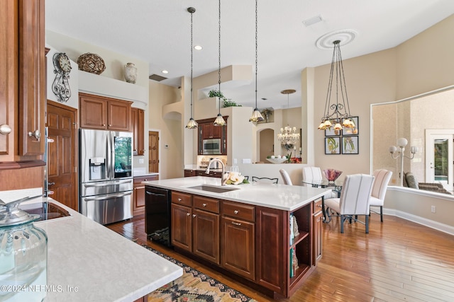 kitchen with pendant lighting, an inviting chandelier, sink, an island with sink, and appliances with stainless steel finishes