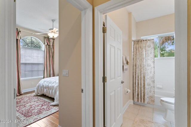 bathroom with tile patterned floors, ceiling fan, toilet, and shower / tub combo