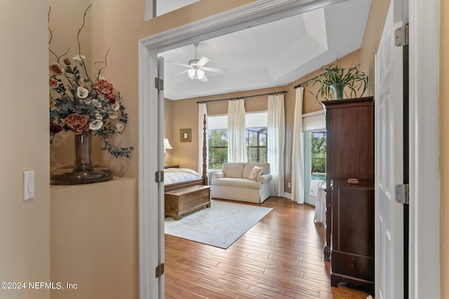 doorway featuring a raised ceiling, ceiling fan, and light hardwood / wood-style flooring