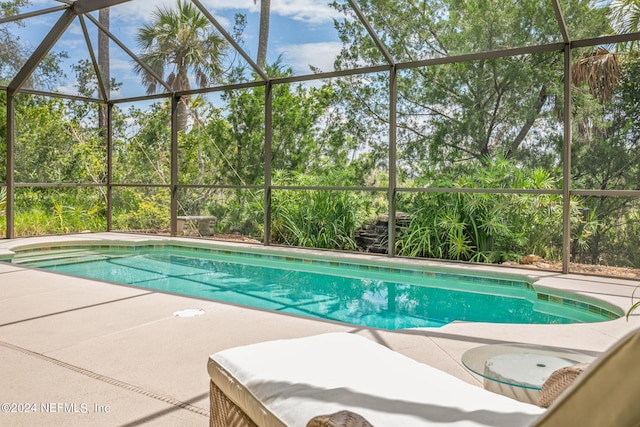 view of pool with glass enclosure and a patio