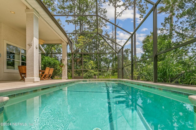 view of swimming pool with glass enclosure and a patio area