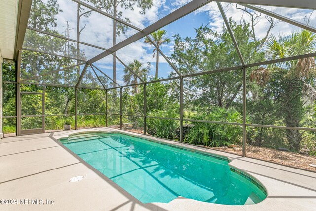 view of swimming pool with glass enclosure and a patio area