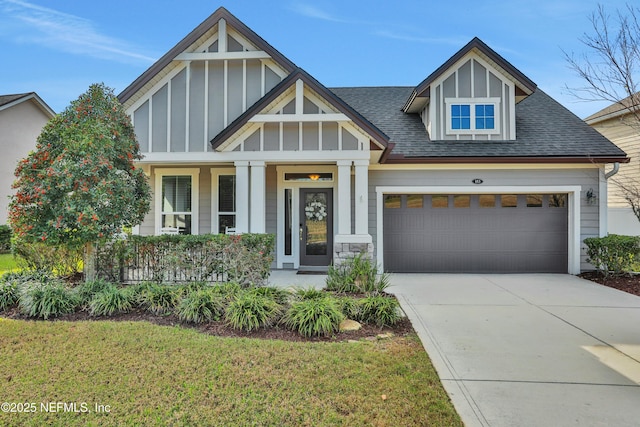 view of front of property featuring covered porch, a garage, and a front lawn