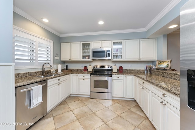 kitchen with dark stone counters, white cabinets, sink, light tile patterned flooring, and stainless steel appliances