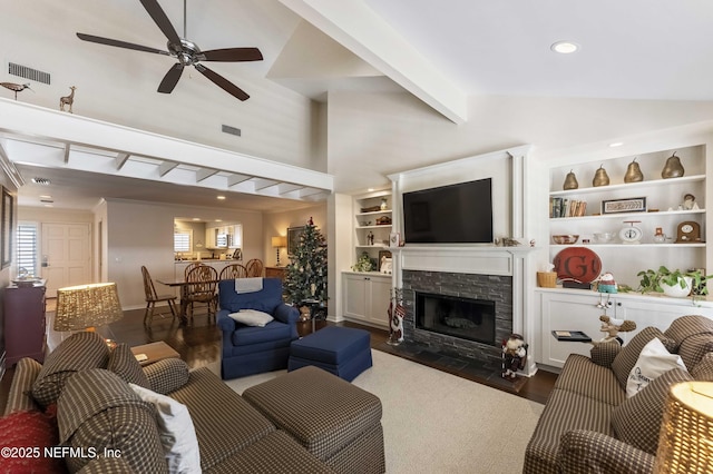 living room featuring vaulted ceiling with beams, dark hardwood / wood-style floors, a stone fireplace, and ceiling fan