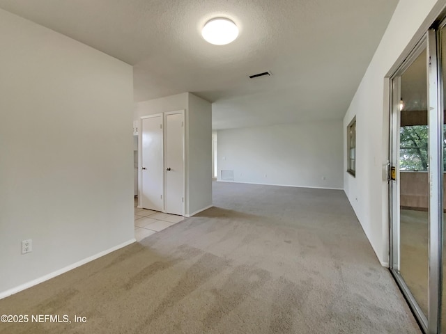 unfurnished room featuring light carpet and a textured ceiling