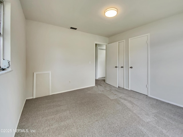 unfurnished bedroom with carpet flooring and multiple closets