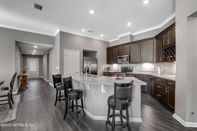 kitchen featuring a breakfast bar, stainless steel appliances, a kitchen island with sink, and dark wood-type flooring