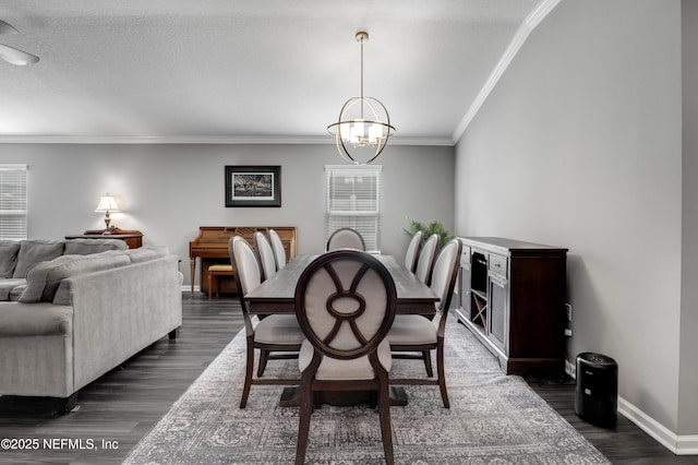 dining area with ornamental molding, a textured ceiling, dark wood-type flooring, and a notable chandelier