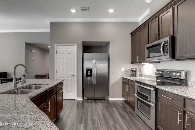 kitchen featuring sink, stainless steel appliances, light stone counters, dark brown cabinets, and ornamental molding