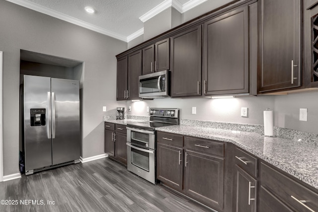 kitchen with dark brown cabinetry, light stone counters, a textured ceiling, appliances with stainless steel finishes, and ornamental molding