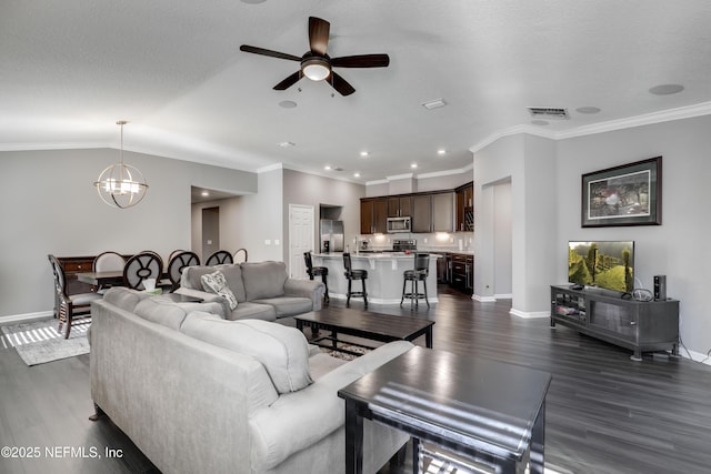 living room featuring ceiling fan with notable chandelier, dark hardwood / wood-style floors, and ornamental molding