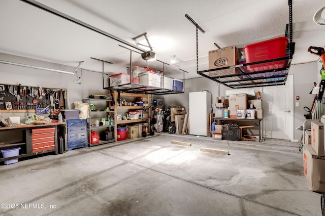 garage with a workshop area, a garage door opener, and white refrigerator