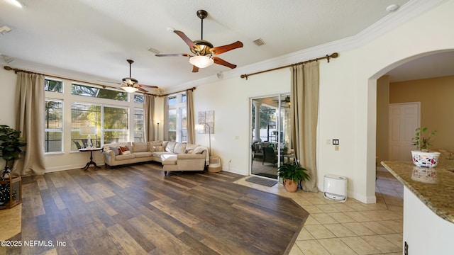 tiled living room featuring crown molding, ceiling fan, and a textured ceiling