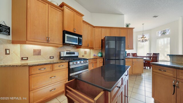 kitchen with a chandelier, appliances with stainless steel finishes, light tile patterned floors, and a kitchen island