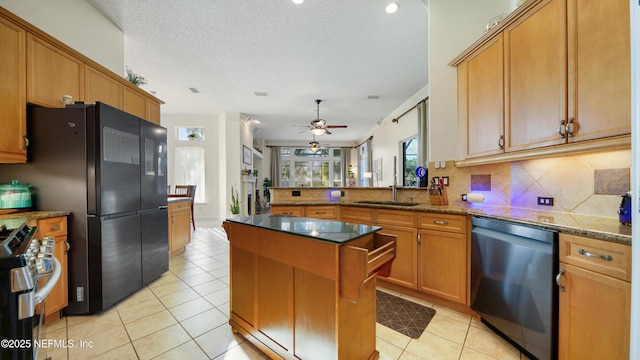 kitchen featuring kitchen peninsula, stainless steel appliances, ceiling fan, light tile patterned floors, and a center island