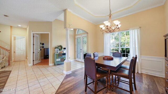 tiled dining space featuring a tray ceiling, french doors, ornamental molding, and a notable chandelier