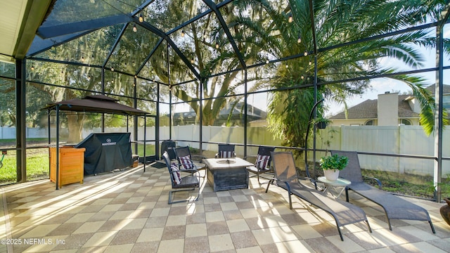 view of patio / terrace with glass enclosure, a grill, and an outdoor fire pit