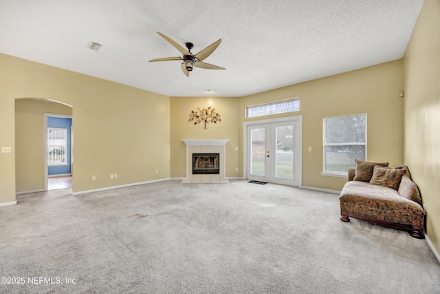 carpeted living room featuring ceiling fan, a fireplace, and a textured ceiling