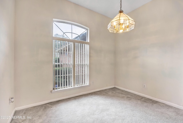 spare room with carpet floors and a chandelier