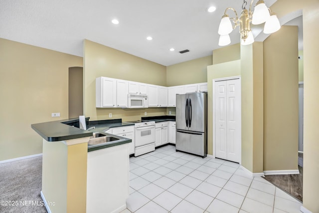 kitchen featuring kitchen peninsula, white appliances, light tile patterned floors, pendant lighting, and white cabinets