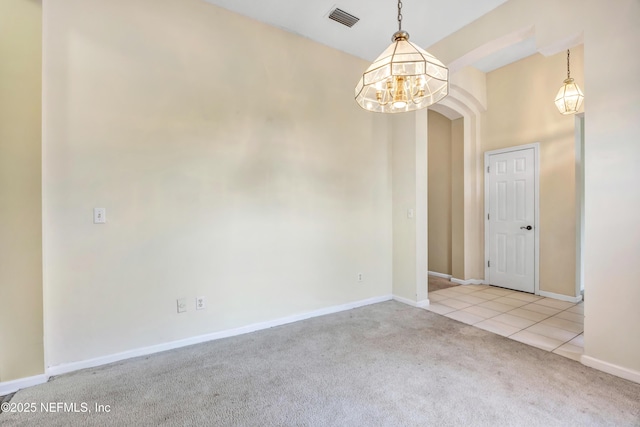 carpeted empty room with a chandelier