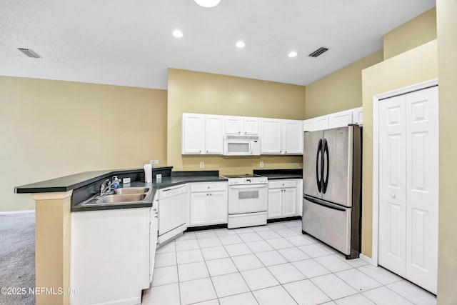 kitchen featuring white appliances, sink, kitchen peninsula, light tile patterned flooring, and white cabinetry