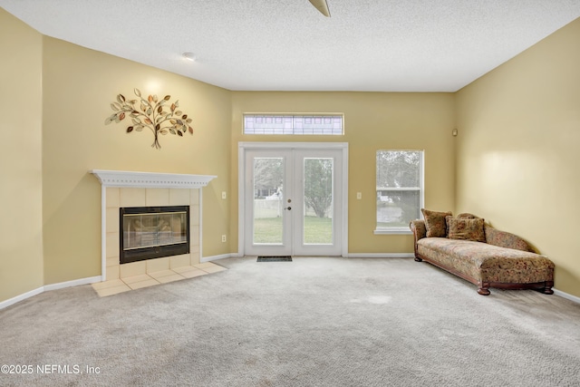 carpeted living room with french doors, a textured ceiling, and a tiled fireplace