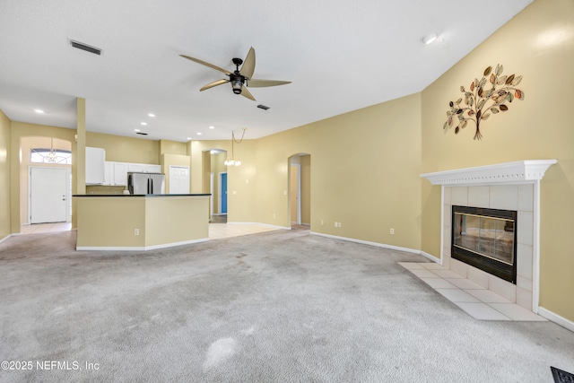 unfurnished living room featuring ceiling fan, light carpet, and a tile fireplace