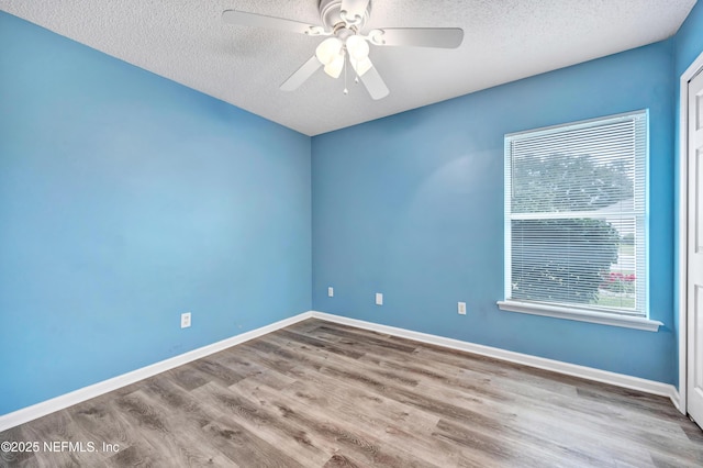 empty room with ceiling fan, light hardwood / wood-style floors, and a textured ceiling