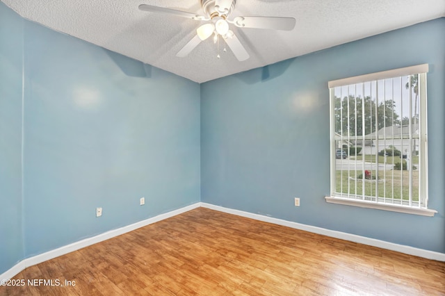 spare room with a wealth of natural light, ceiling fan, wood-type flooring, and a textured ceiling