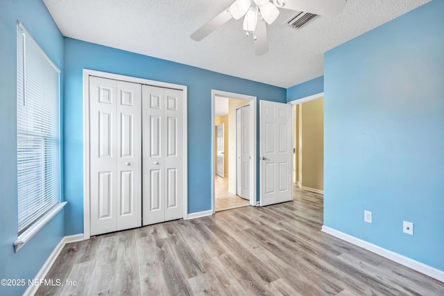 unfurnished bedroom featuring a textured ceiling, a closet, ceiling fan, and light hardwood / wood-style floors