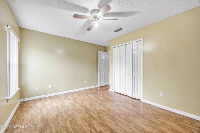 unfurnished bedroom with ceiling fan, light hardwood / wood-style floors, a textured ceiling, and a closet