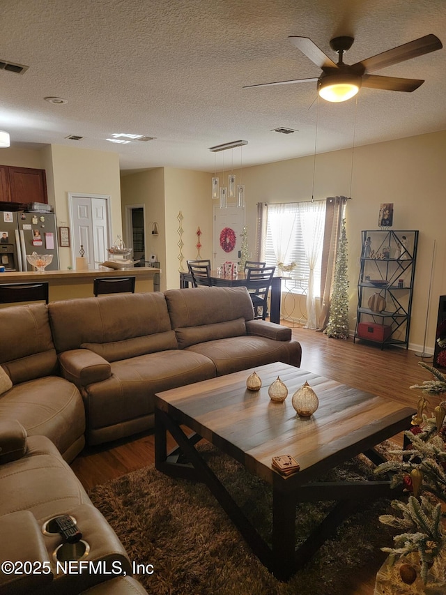 living room featuring ceiling fan, wood-type flooring, and a textured ceiling