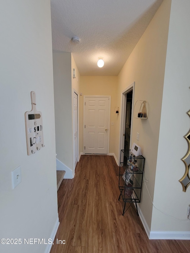 corridor with dark hardwood / wood-style floors and a textured ceiling