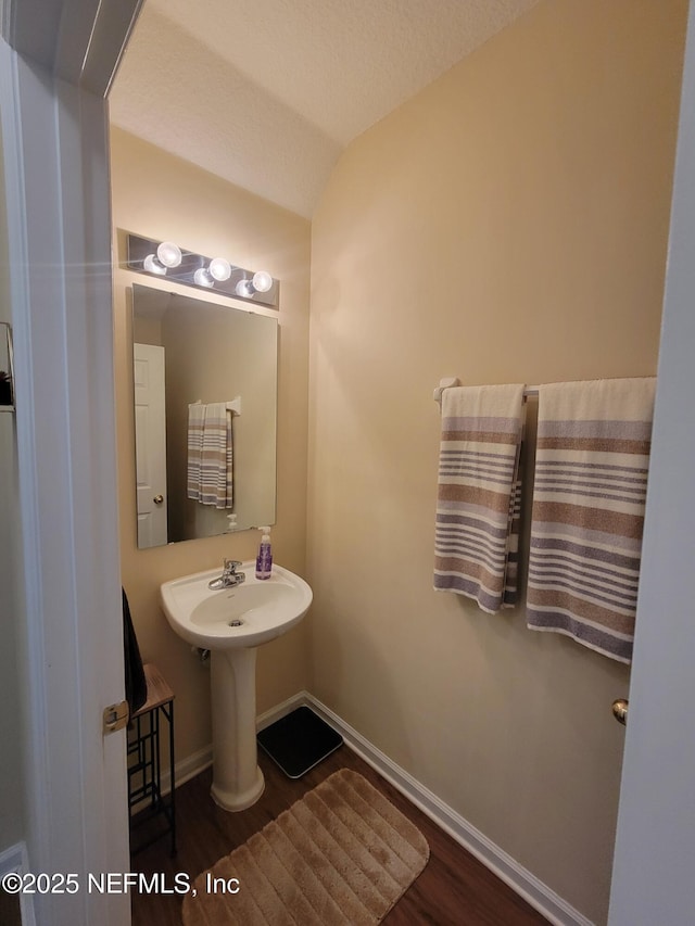 bathroom featuring hardwood / wood-style flooring, a textured ceiling, and vaulted ceiling