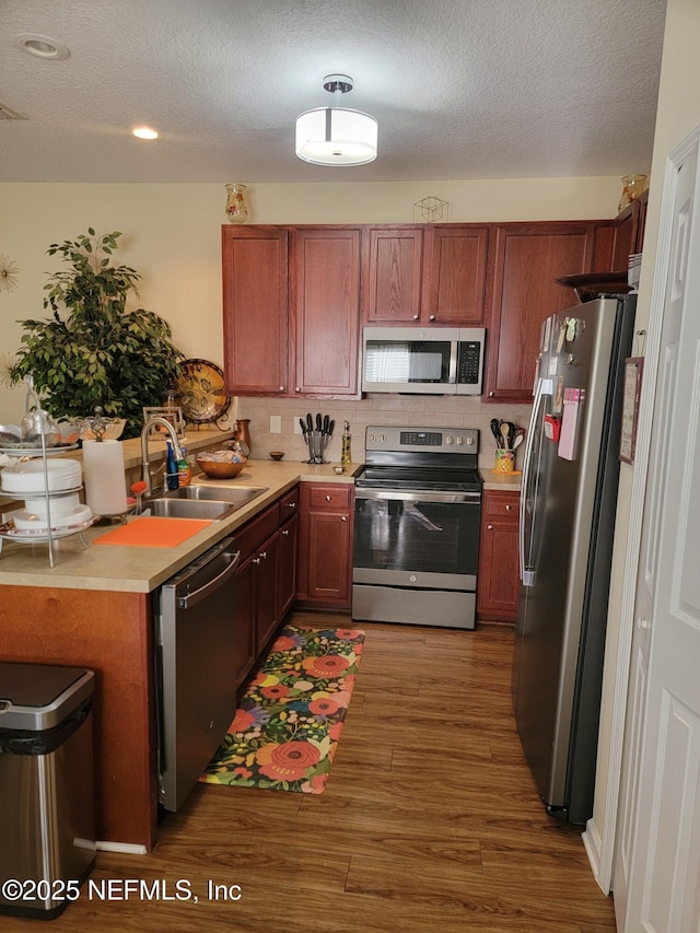 kitchen with appliances with stainless steel finishes, tasteful backsplash, dark wood-type flooring, and sink