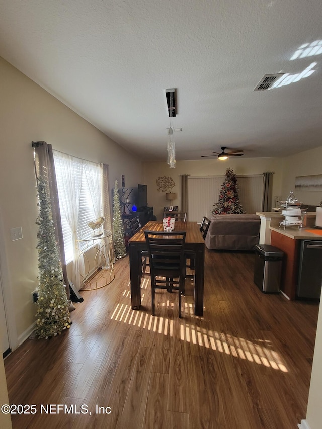 dining room with a textured ceiling, ceiling fan, and dark hardwood / wood-style floors