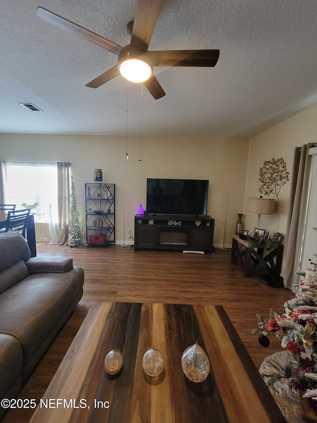 living room featuring wood-type flooring, a textured ceiling, and ceiling fan